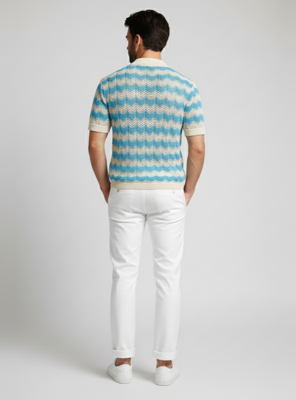 Man wearing a striped shirt and white pants on a plain background