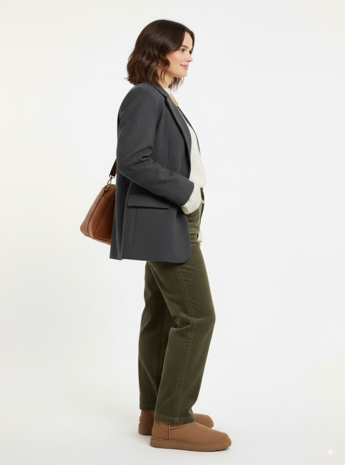Woman wearing a gray blazer, white shirt, green pants, and brown boots on a white background