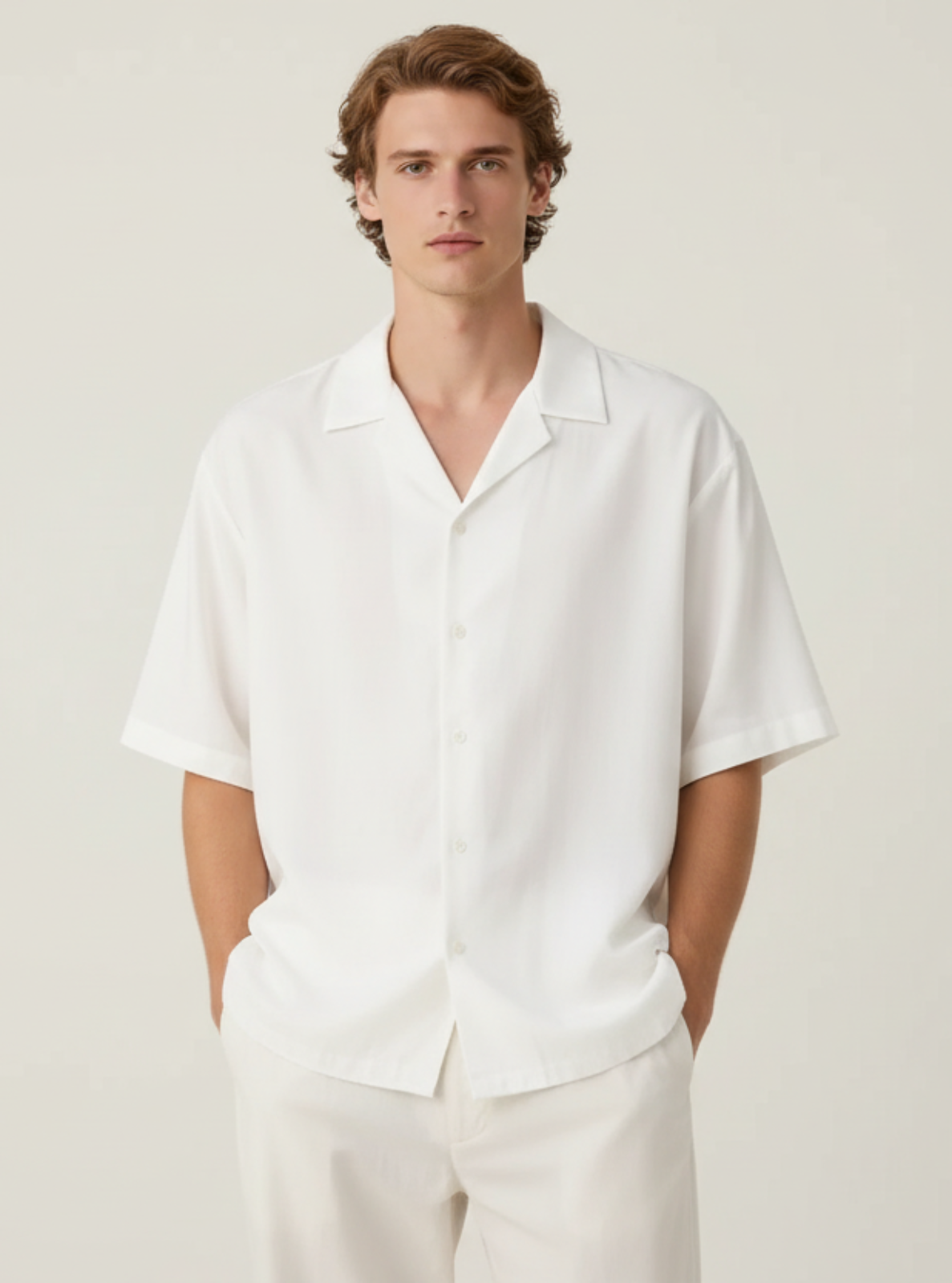 Man wearing a white shirt and pants against a plain background