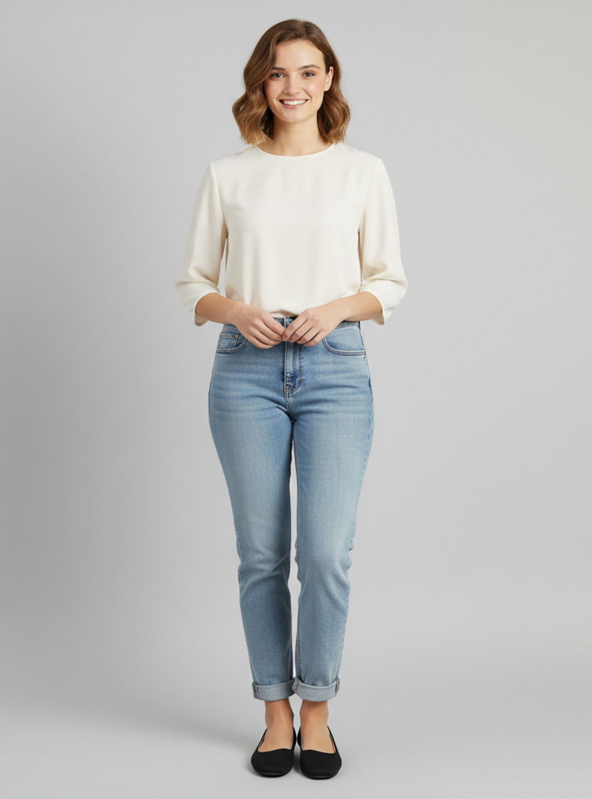 Woman wearing a white sweater and light blue jeans on a gray background