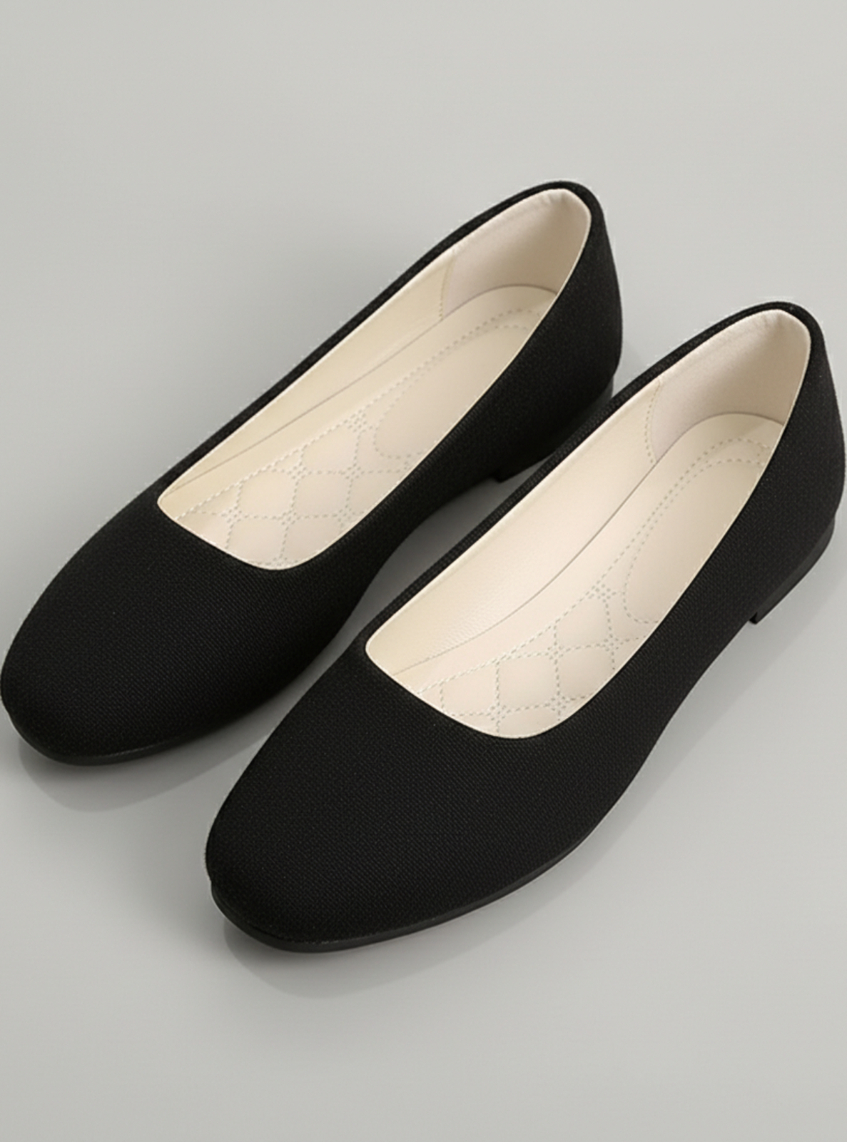 Pair of black flat shoes on a gray background