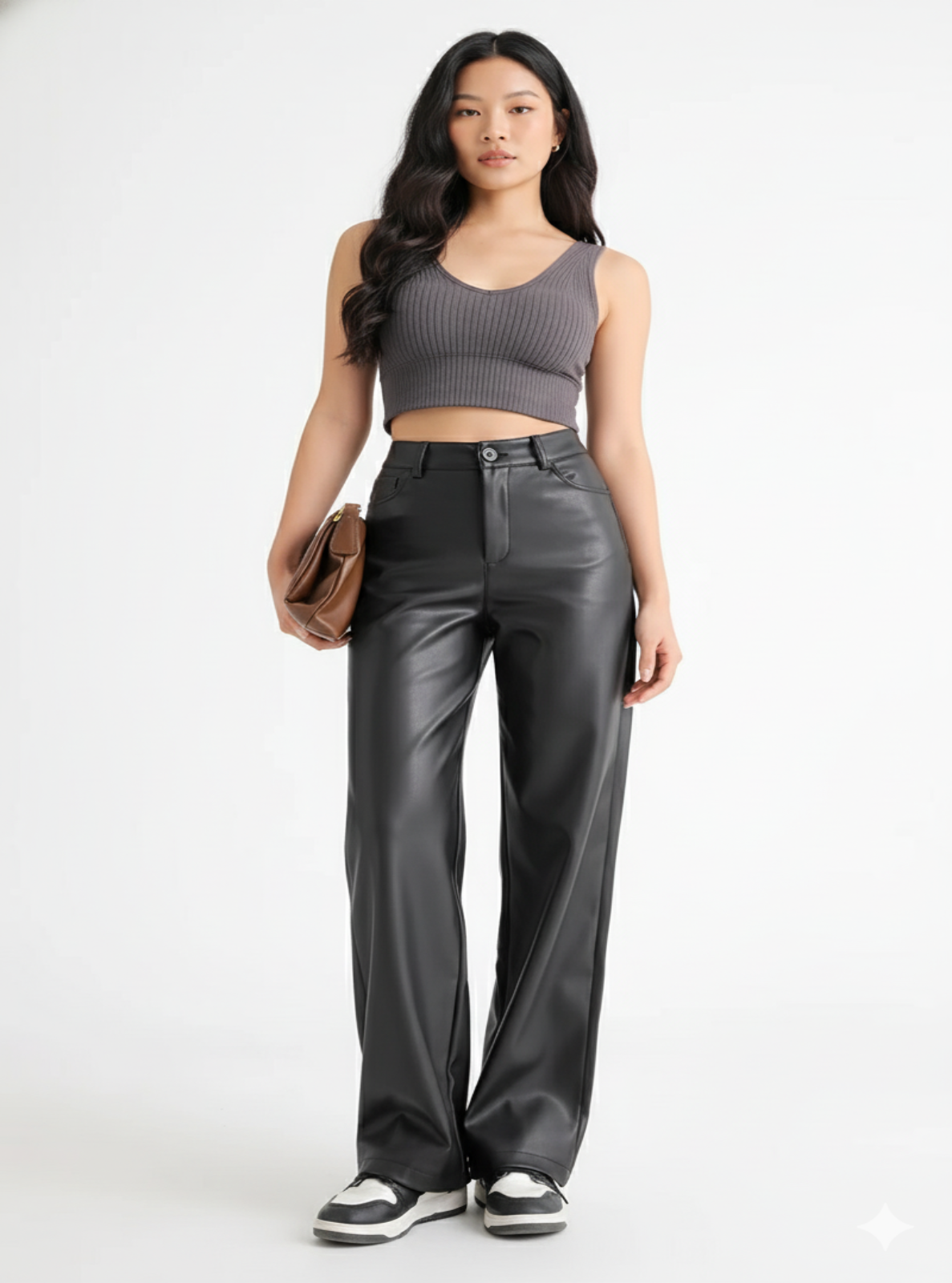 Woman wearing a gray tank top and black leather pants on a white background
