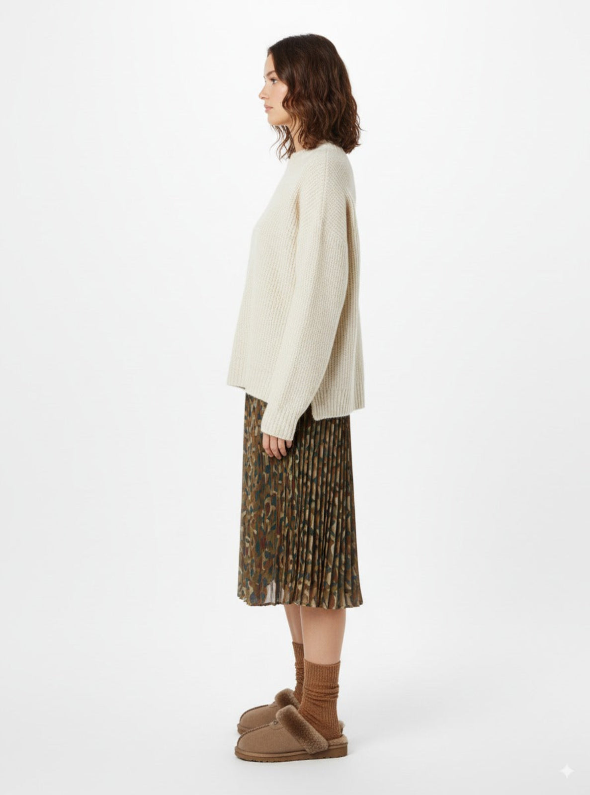 Woman wearing a cream sweater and patterned skirt with brown shoes on a white background