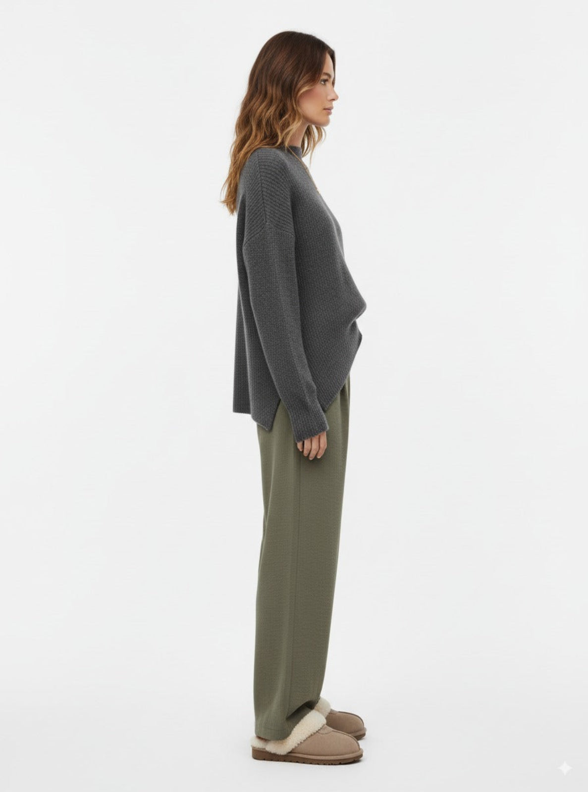 Woman wearing a gray sweater and green pants on a white background