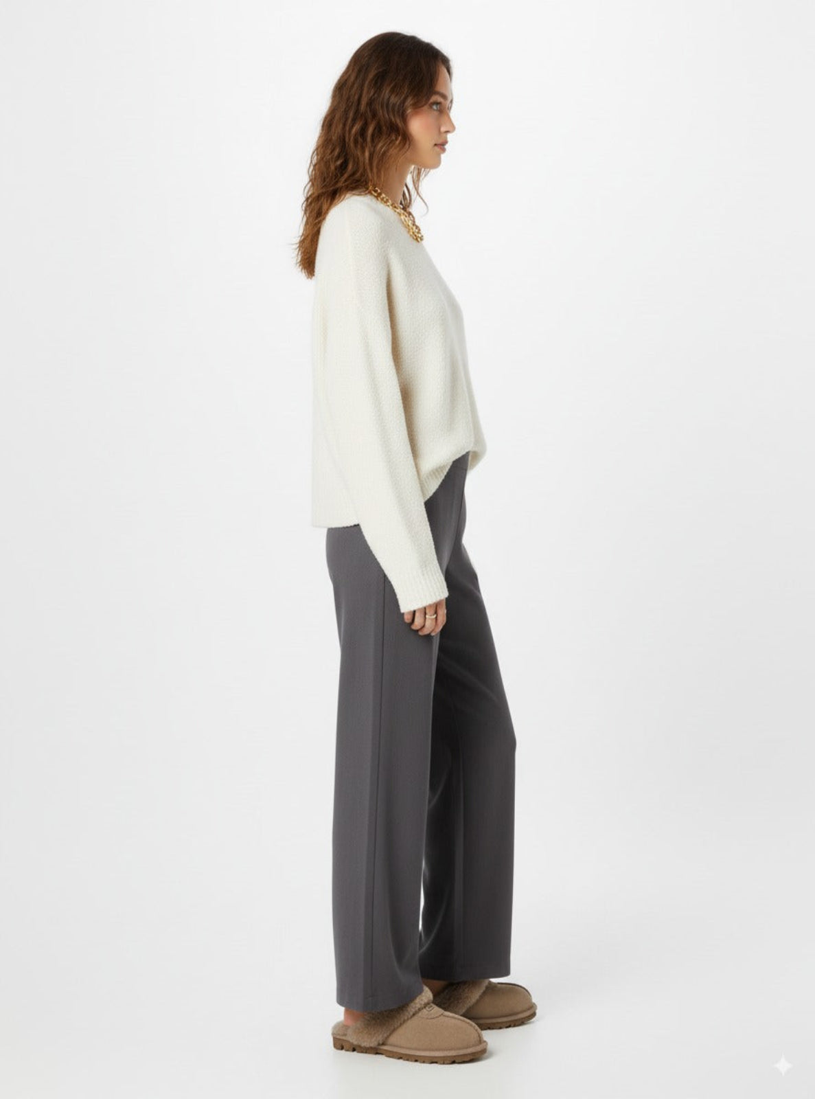Woman wearing a white sweater and gray pants on a white background