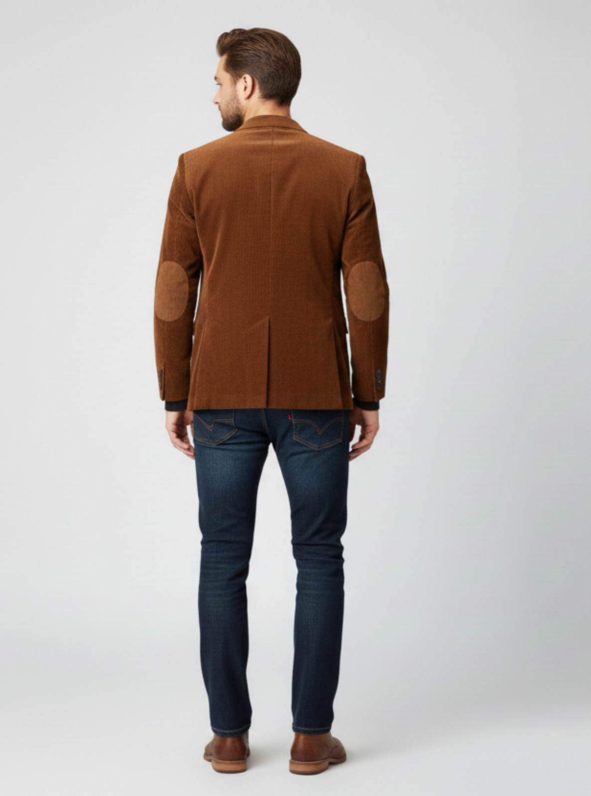 Man wearing a brown jacket and dark jeans on a white background