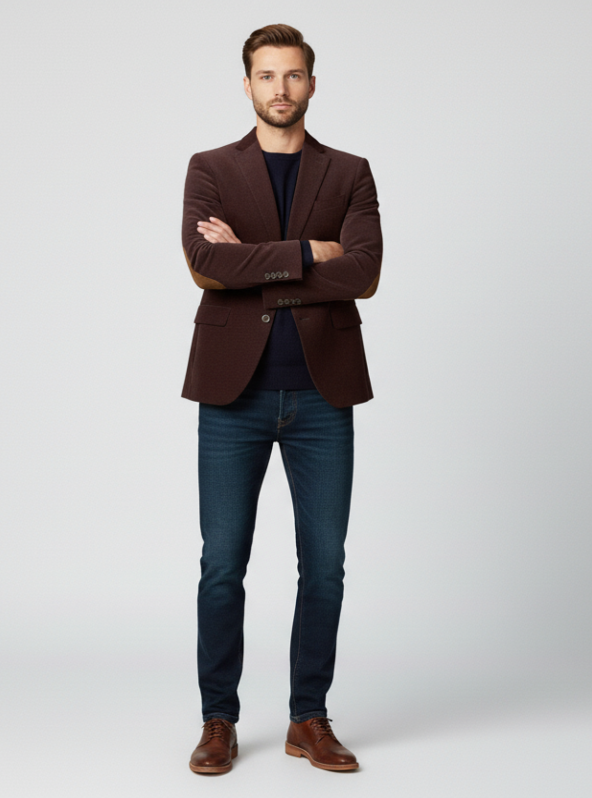 Man wearing a brown blazer, black shirt, and blue jeans on a white background