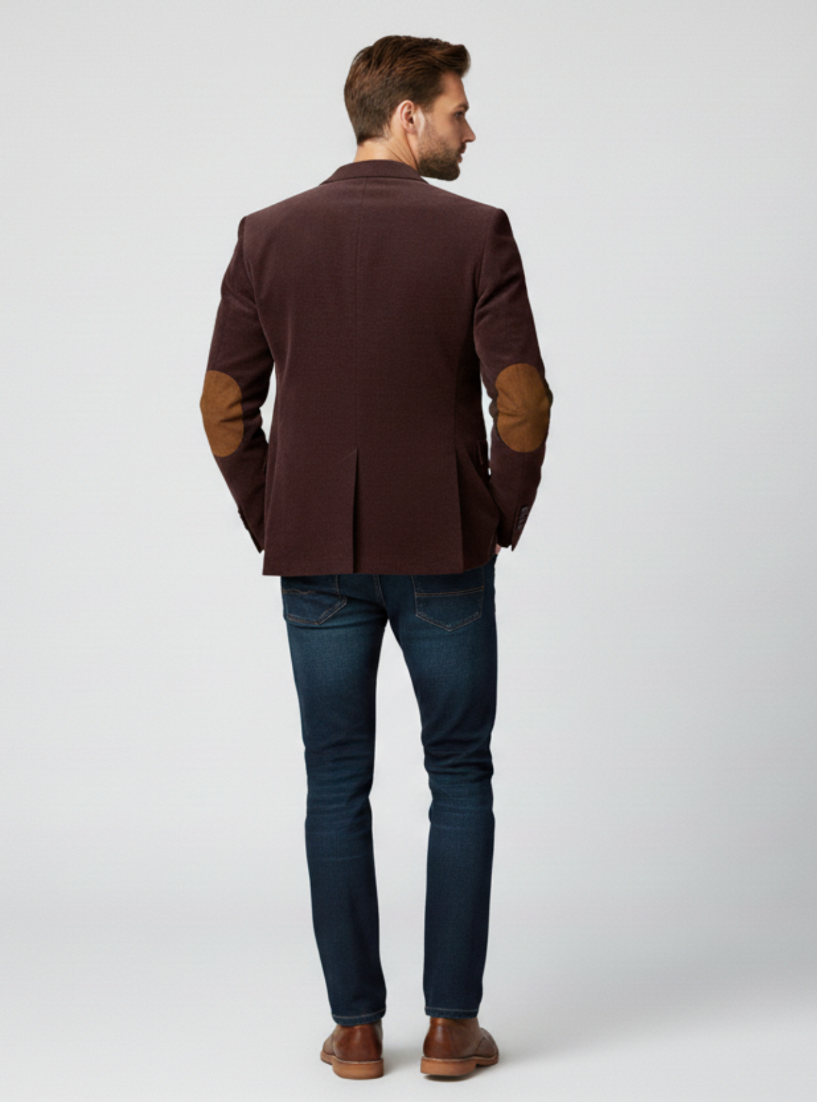 Man wearing a brown blazer and blue jeans on a white background