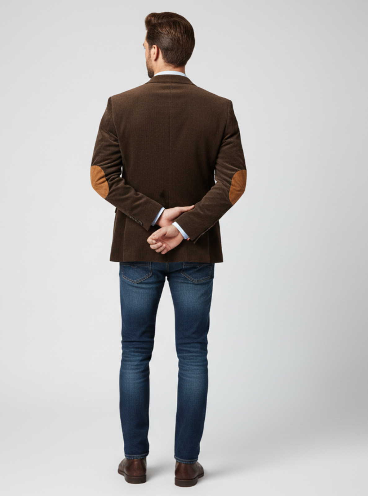 Man wearing a brown blazer and blue jeans on a white background