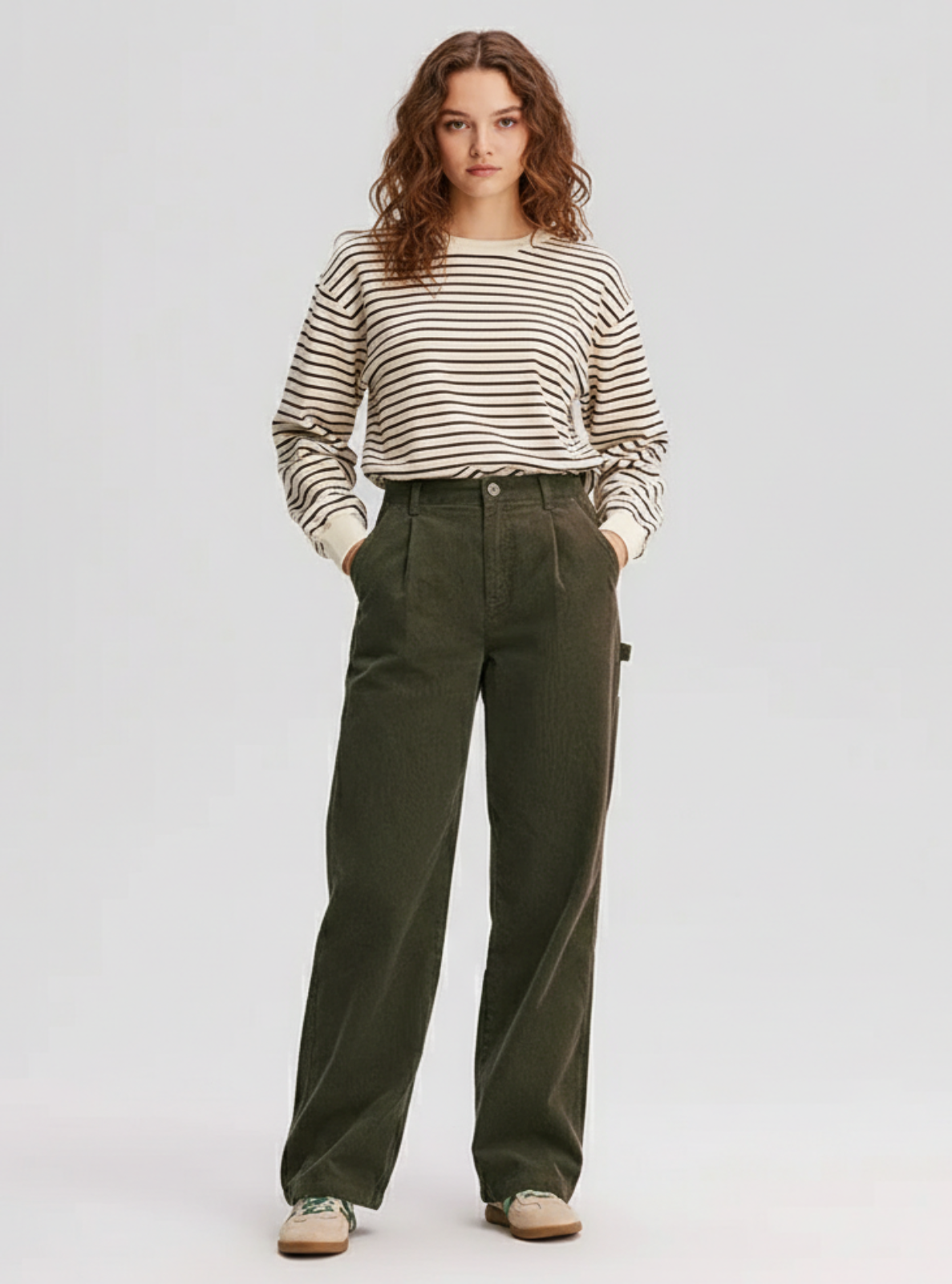 Woman wearing a striped sweater and green pants on a white background