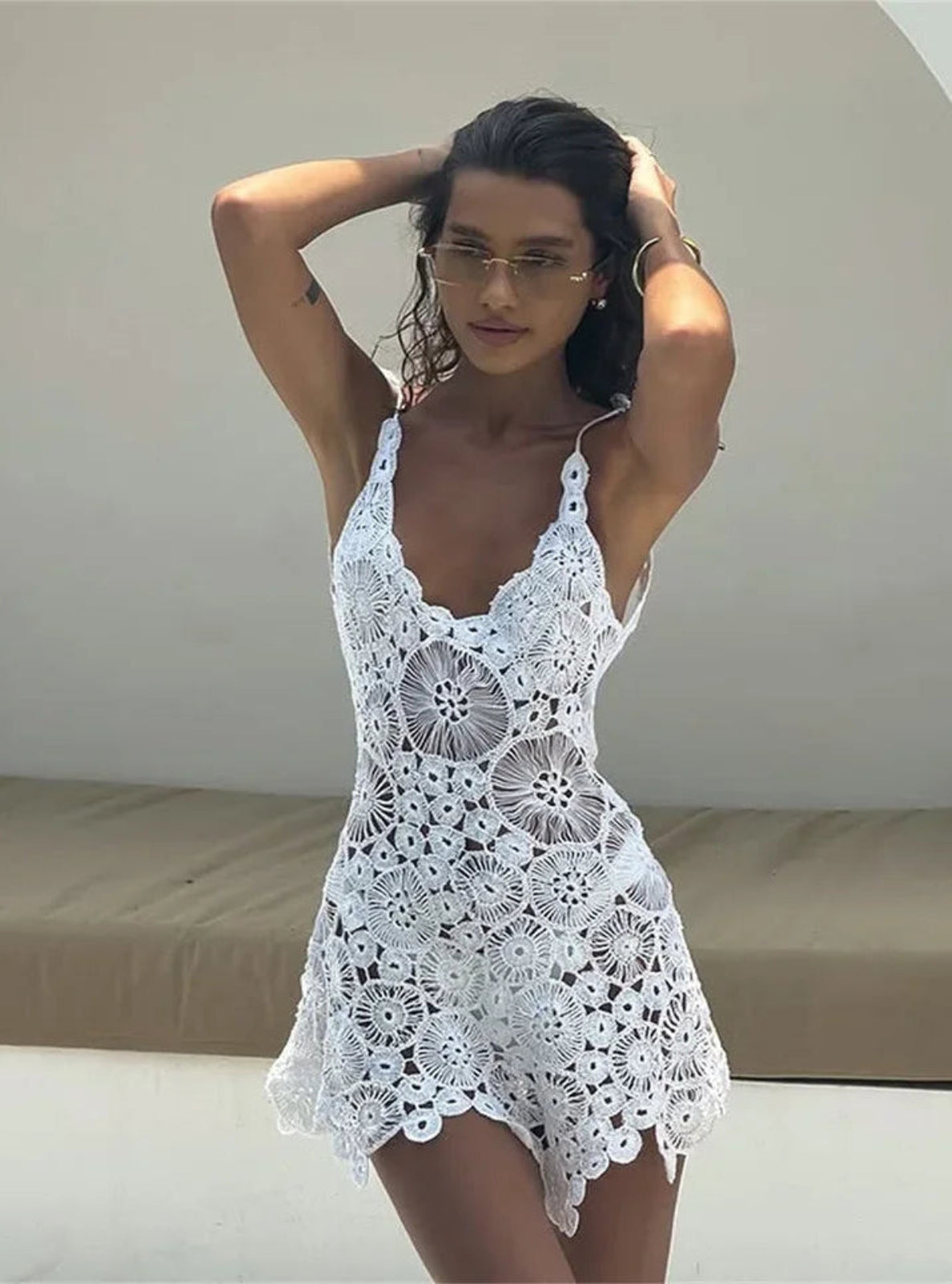 Woman wearing a white crochet dress against a neutral background