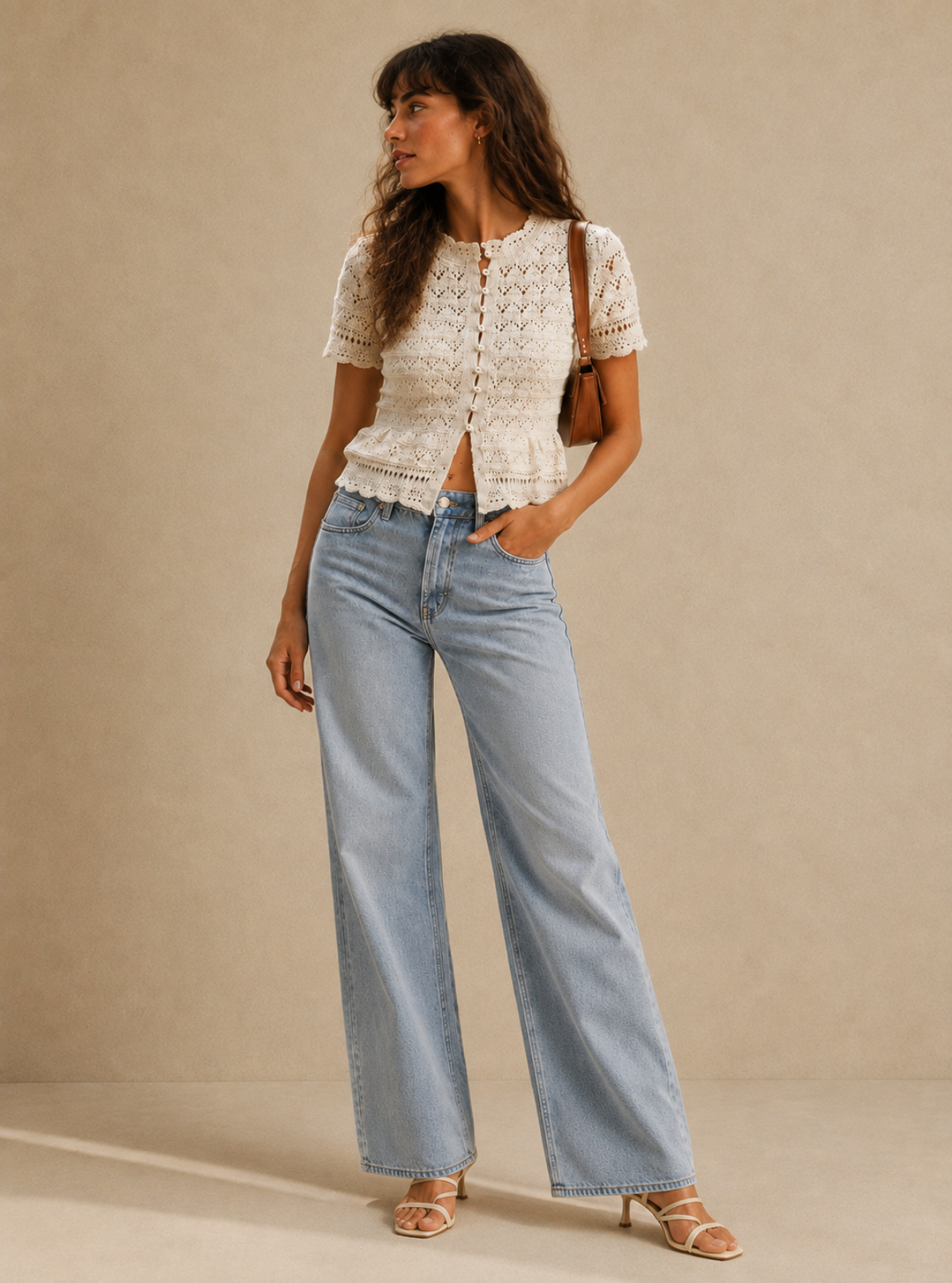 A woman models a short-sleeve cream lace top and light-wash wide-leg jeans against a neutral beige studio backdrop.