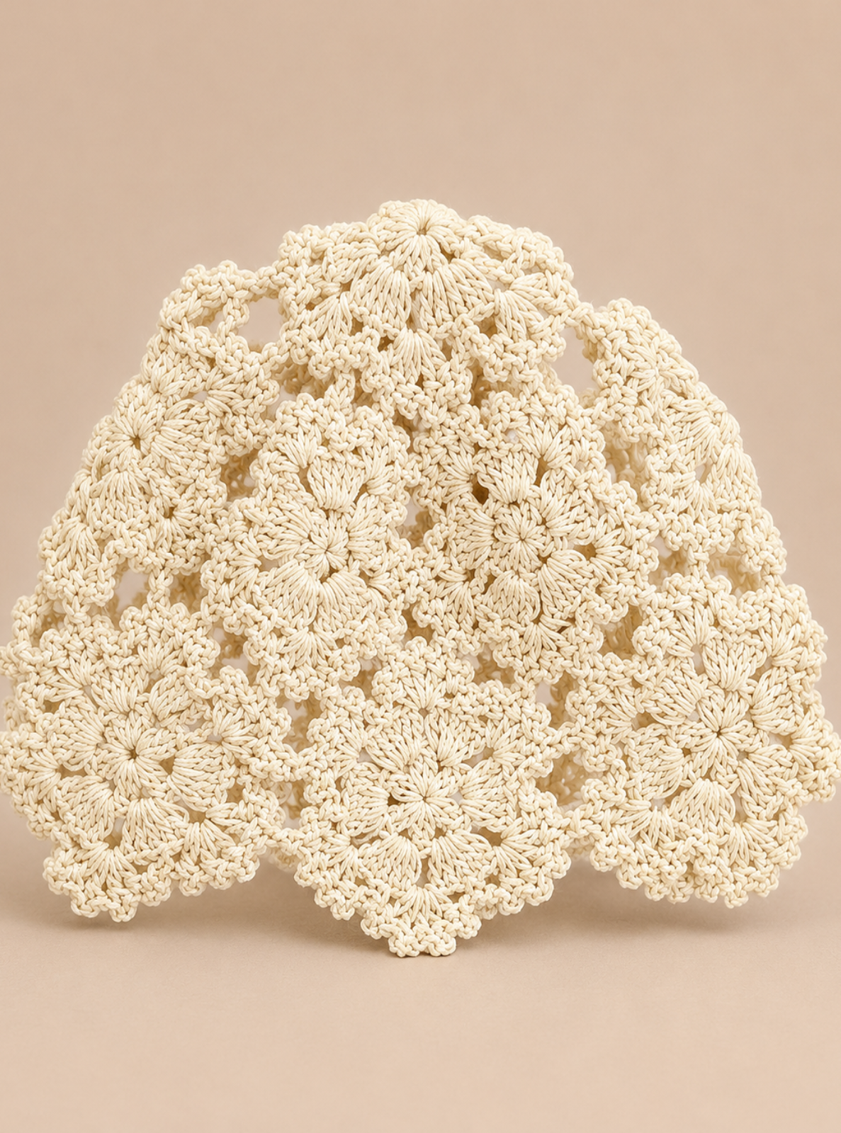 An off-white crocheted lace doily with a scalloped edge, displayed against a solid beige background.