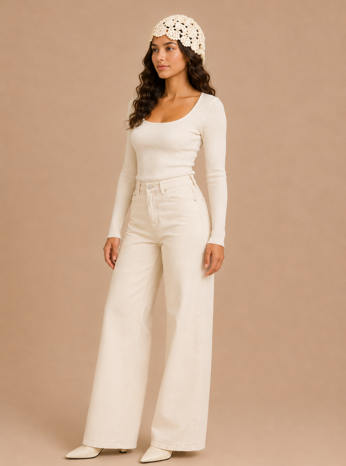 A woman modeling a cream-colored outfit consisting of a long-sleeve scoop-neck top, high-waisted wide-leg pants, and a matching crochet headband, set against a solid beige studio background.