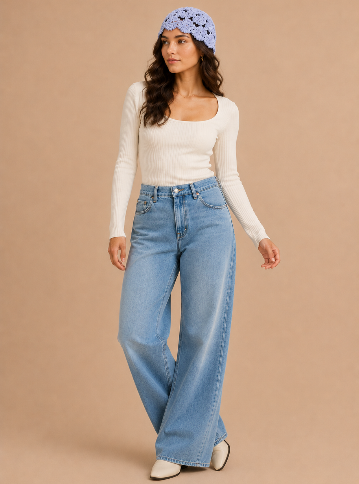 A woman modeling light-wash wide-leg blue jeans, a white long-sleeve top, a light blue patterned headband, and white pointed shoes against a solid beige studio background.