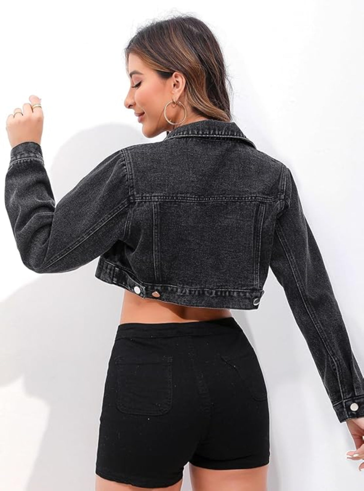 Person wearing a black denim jacket and black shorts on a white background