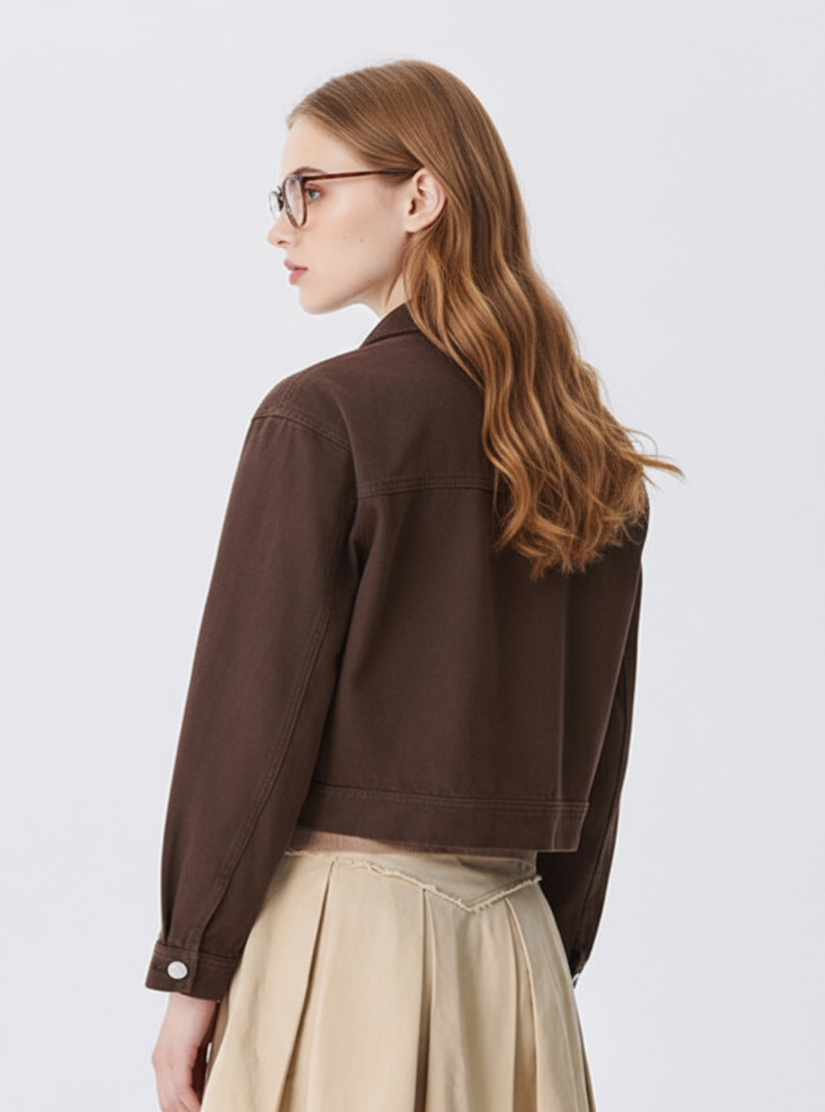 Woman wearing a brown jacket and beige skirt on a white background with SEM/R branding.