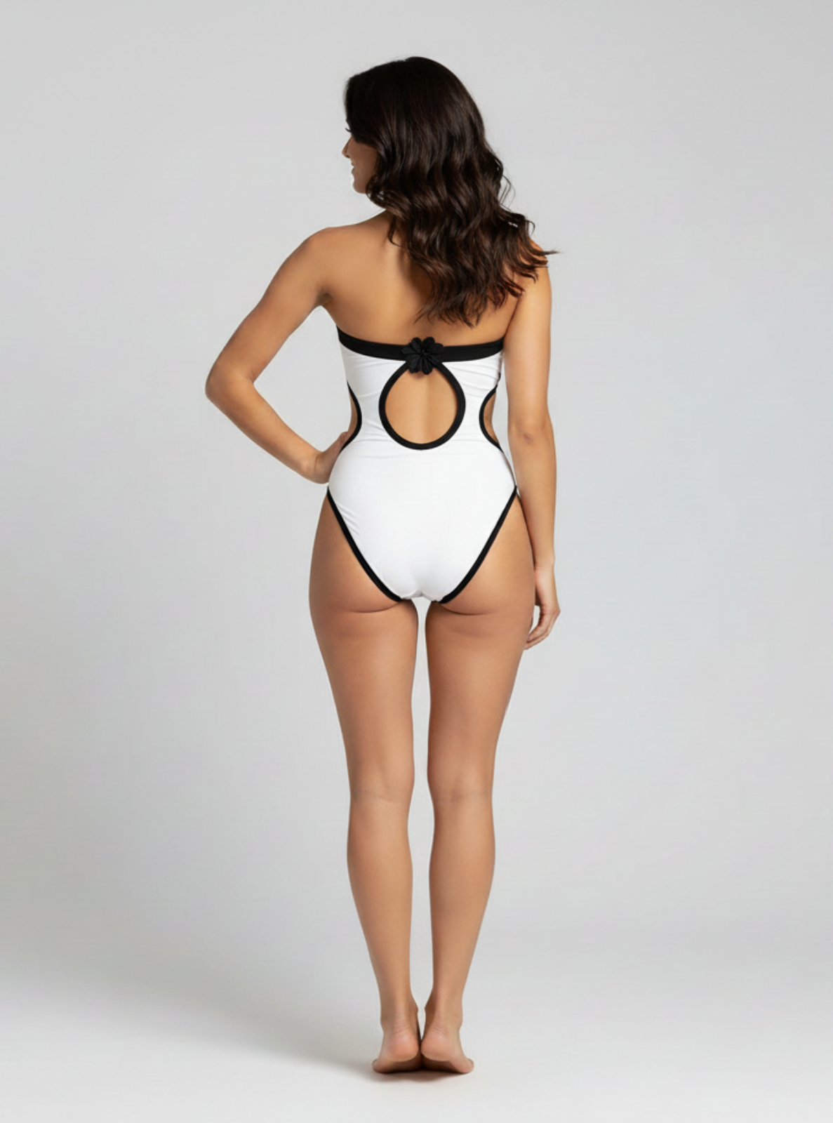 Woman wearing a white swimsuit with black accents on a plain background