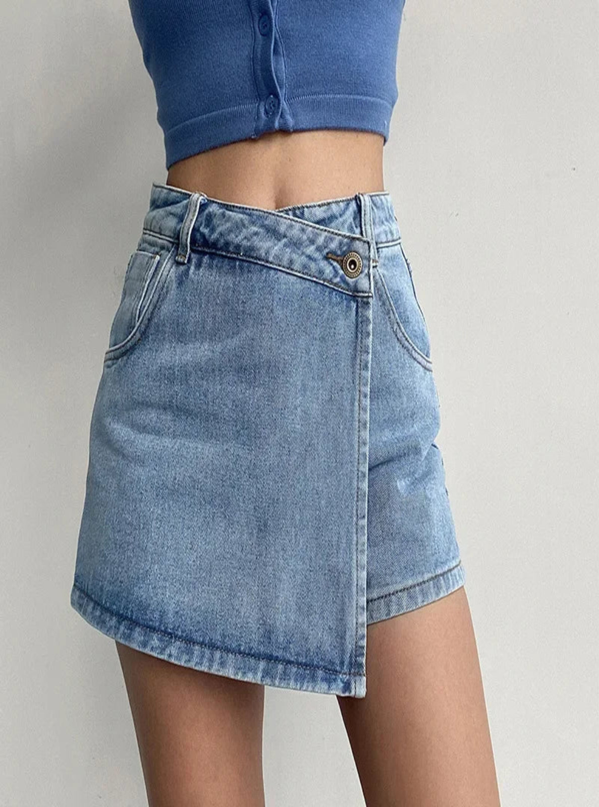 Person wearing a blue denim skirt and blue crop top on a plain background