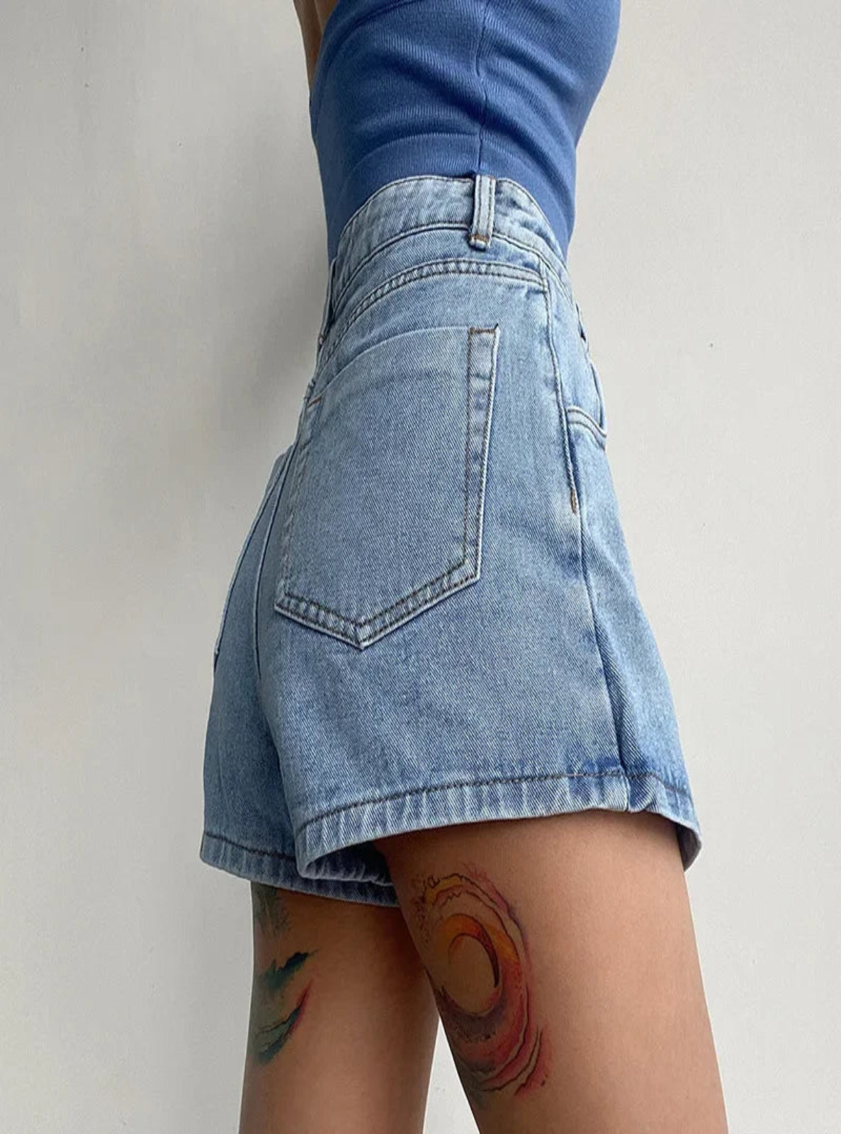Person wearing a blue denim skirt with a plain background