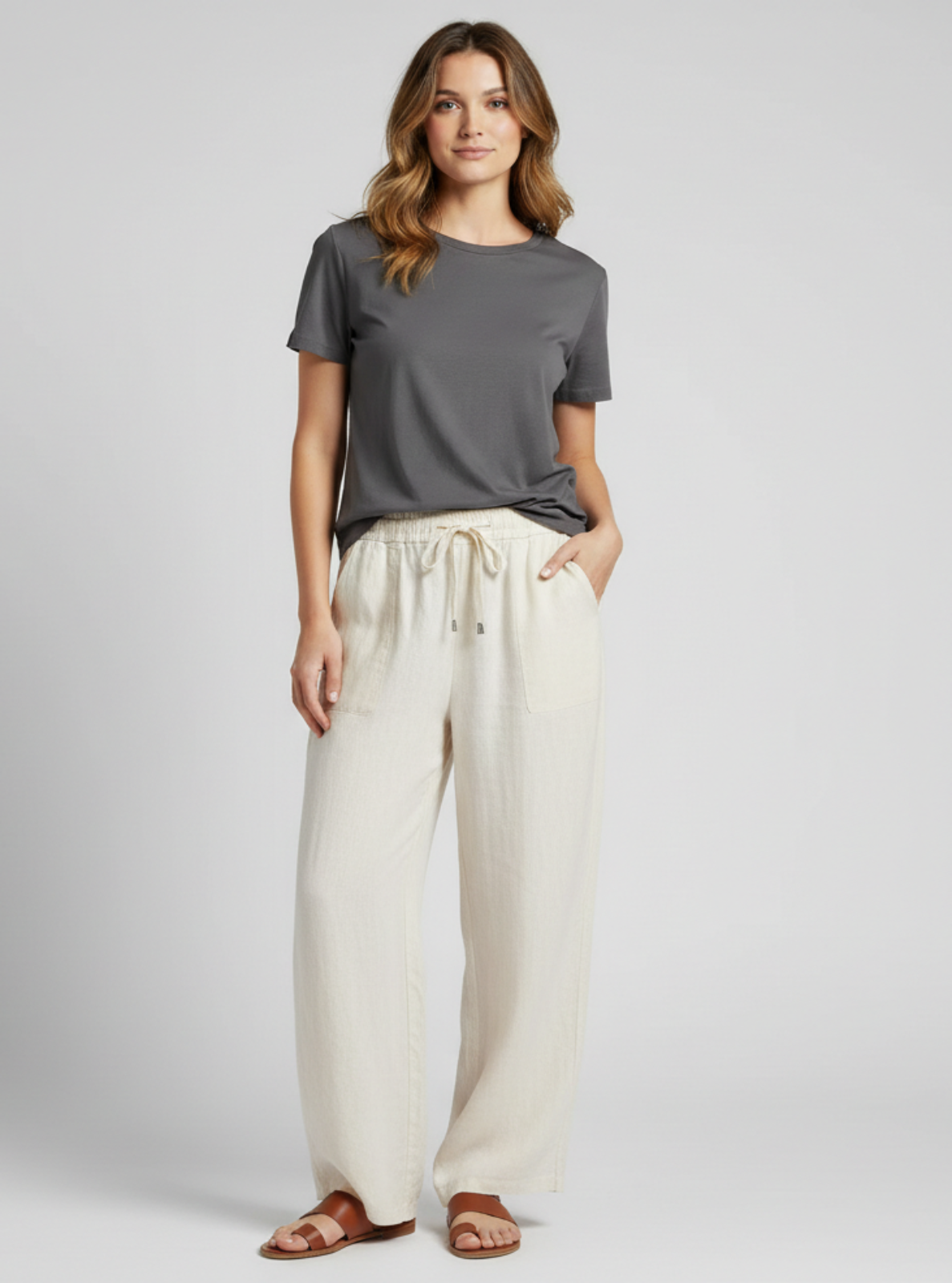 Woman wearing a gray t-shirt and white pants on a plain background