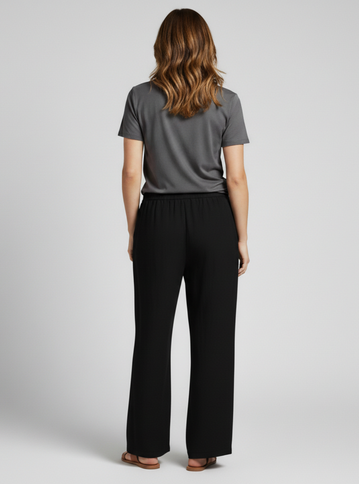 Woman wearing a gray t-shirt and black pants on a light gray background