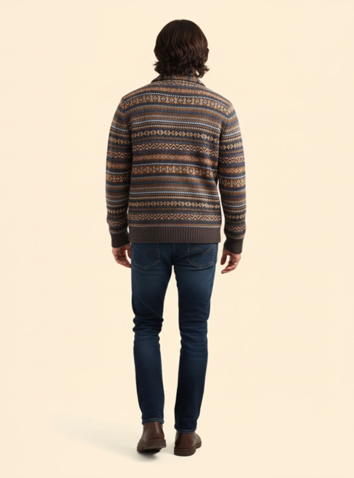 Person wearing a patterned sweater and jeans on a beige background