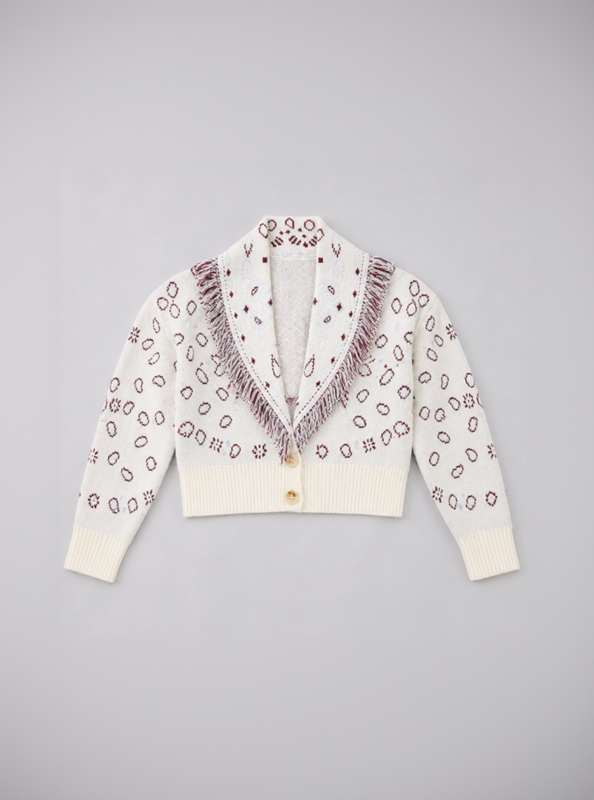 White cardigan with purple pattern and fringes on a gray background