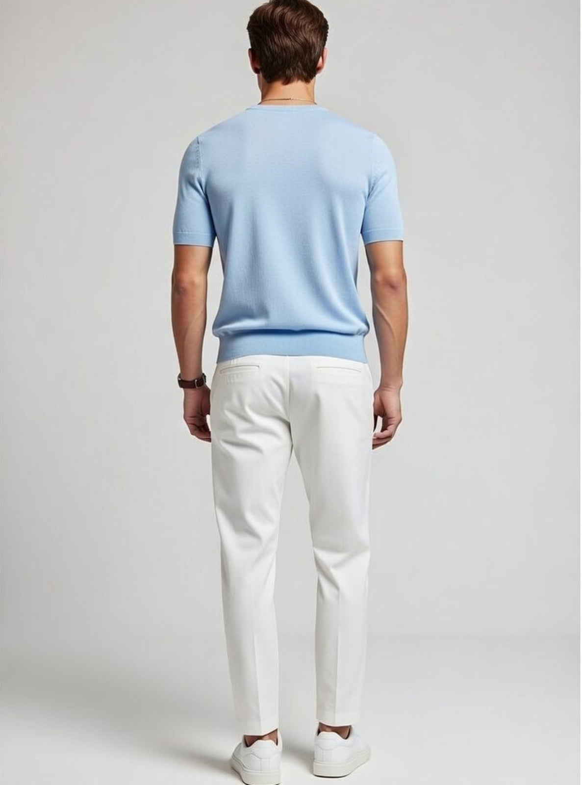 Man wearing a light blue shirt and white pants on a plain background