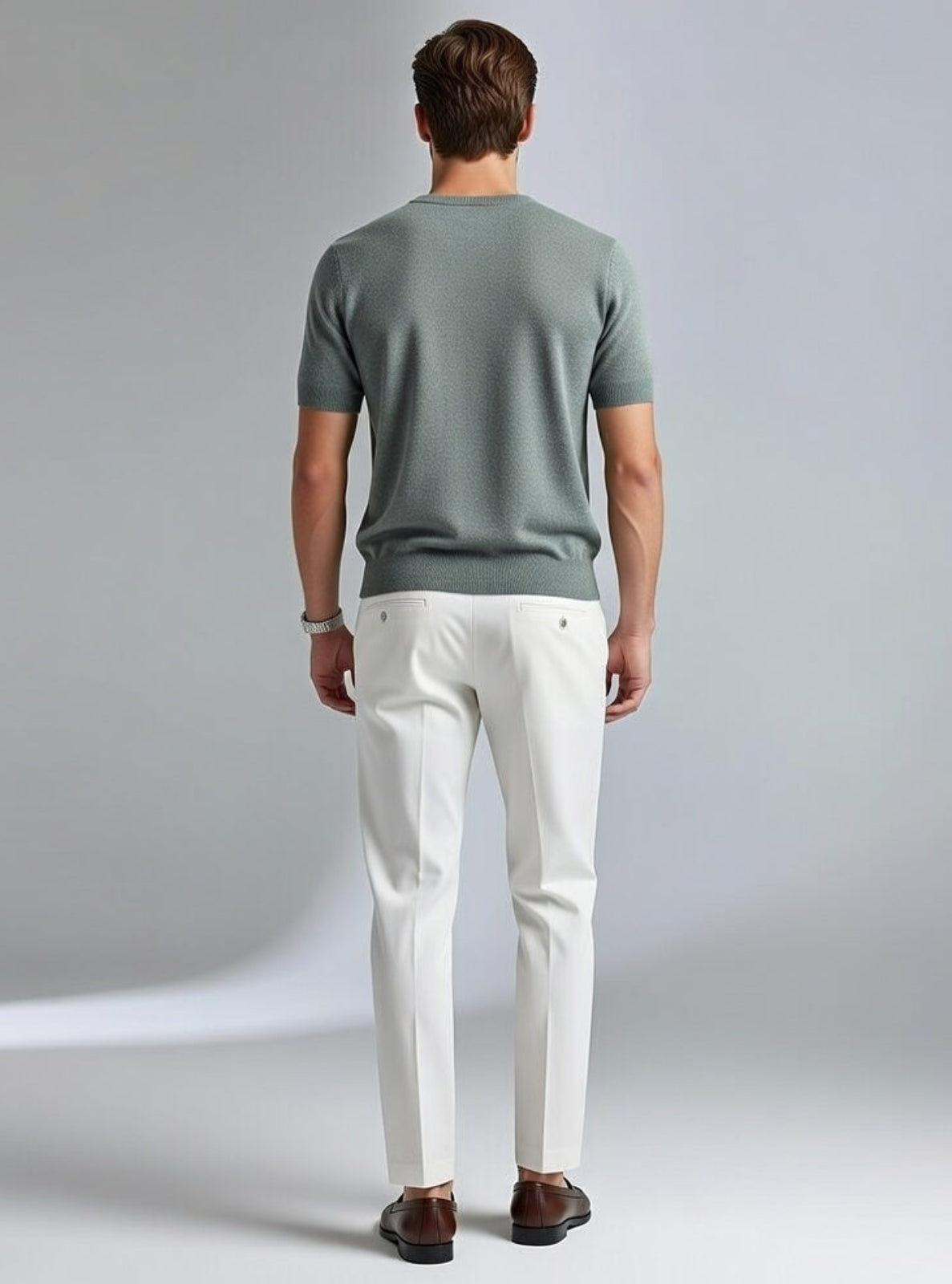 Man wearing a green shirt and white pants on a gray background