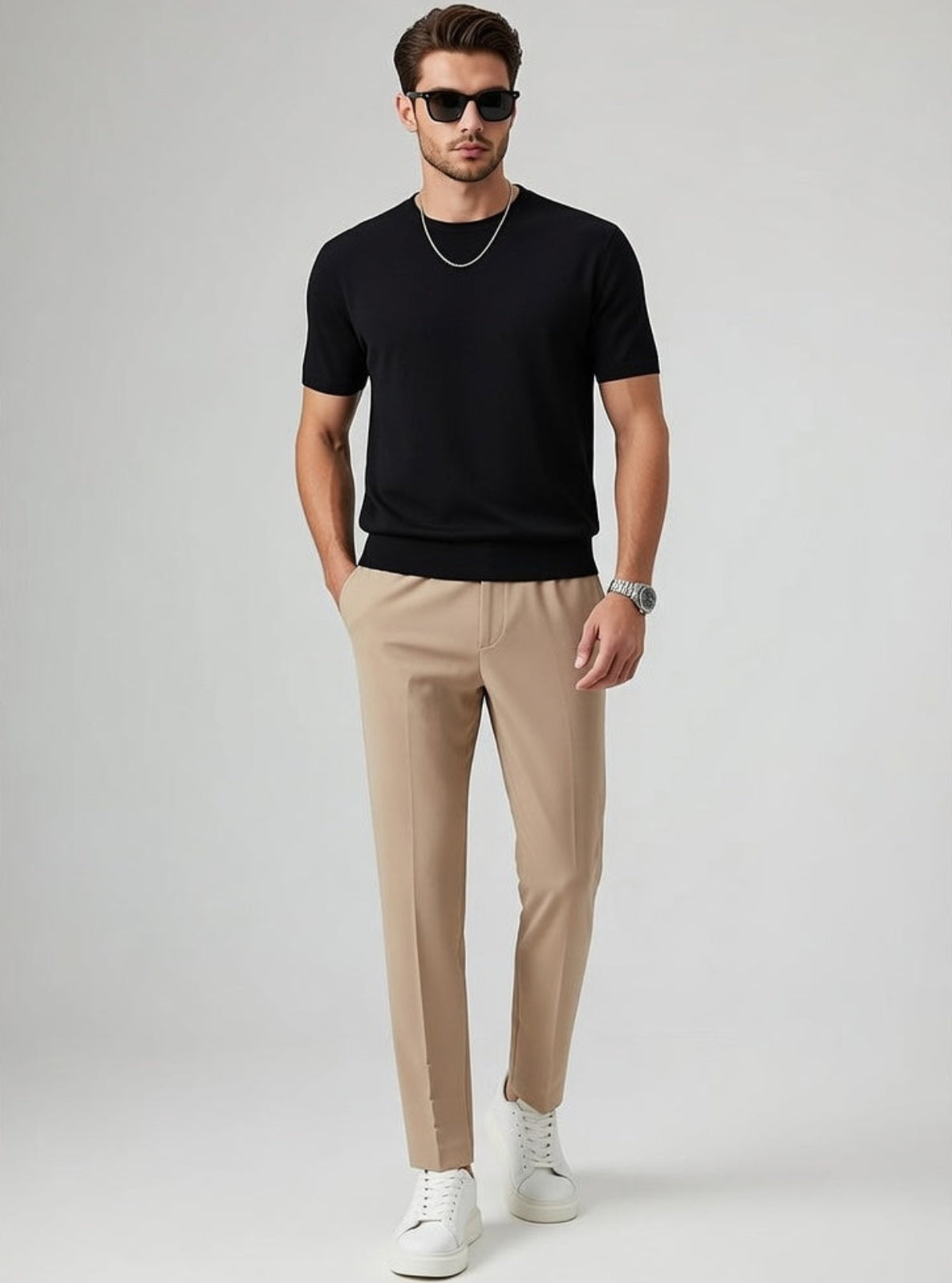 Man wearing a black t-shirt, beige pants, and white sneakers on a gray background