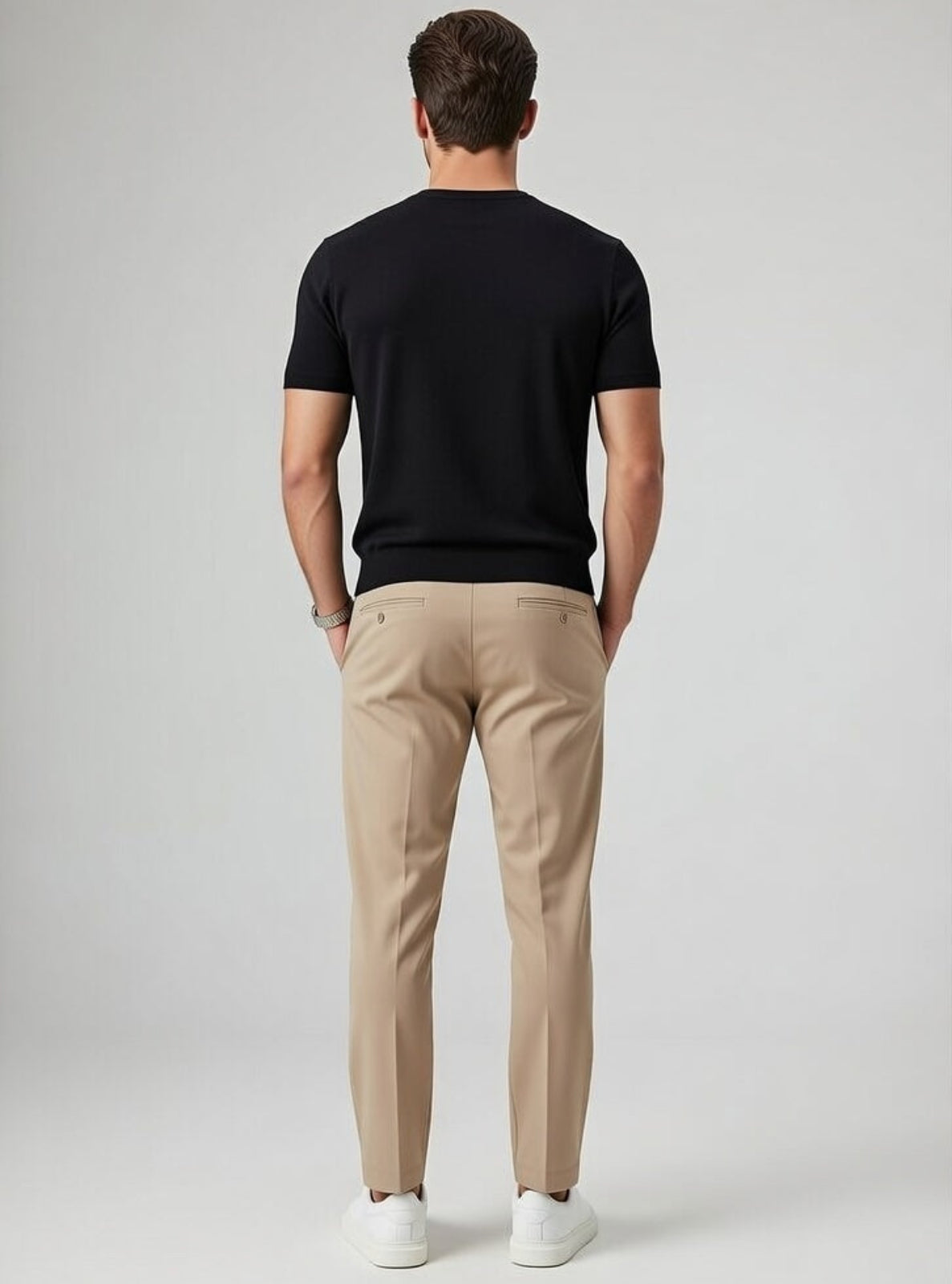 Man wearing a black t-shirt and beige pants on a gray background