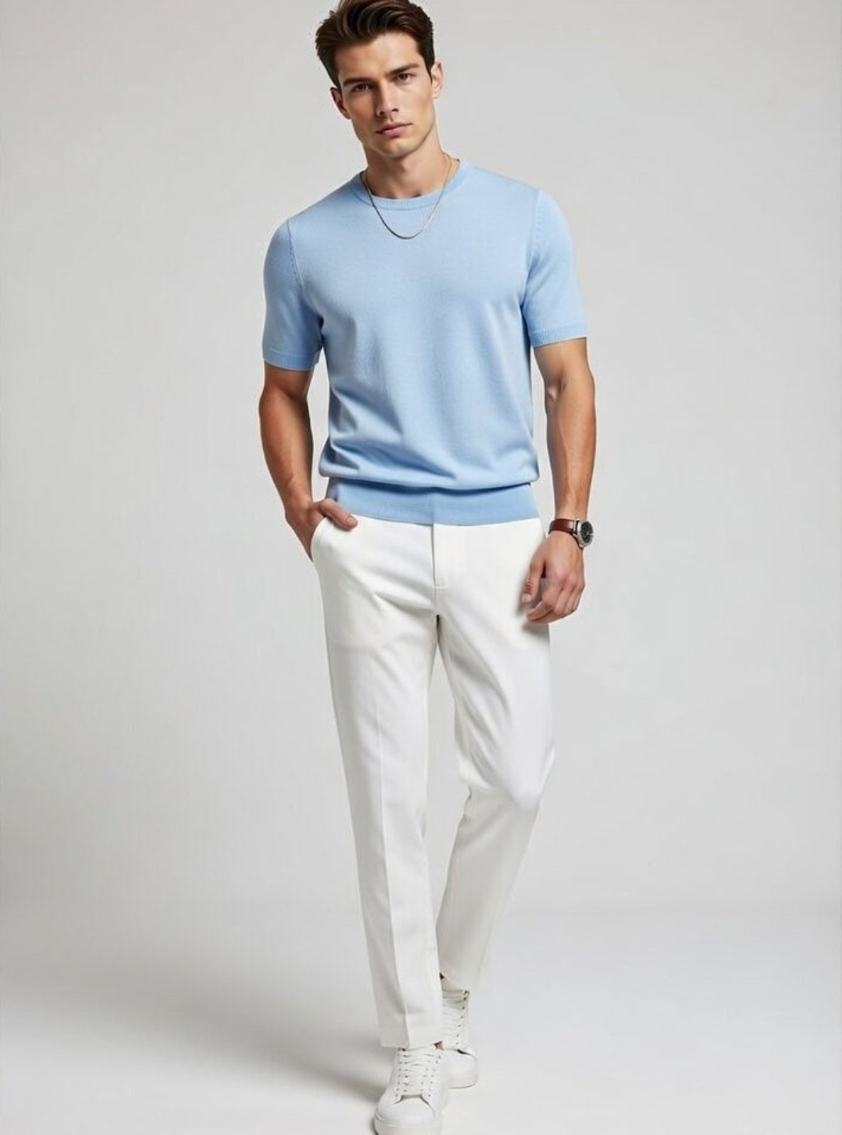 Man wearing a light blue t-shirt and white pants on a gray background