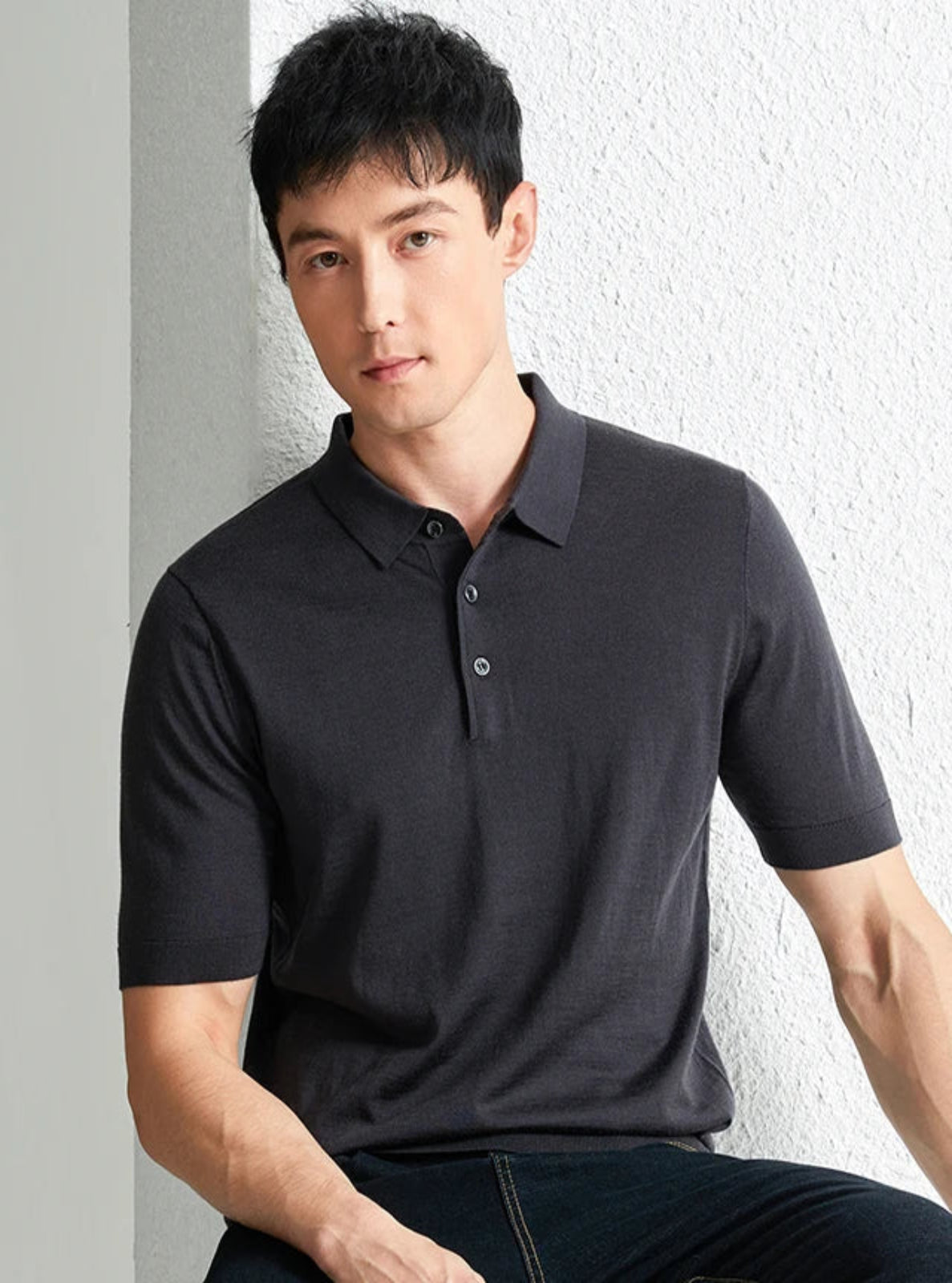 Man wearing a dark gray polo shirt against a light background