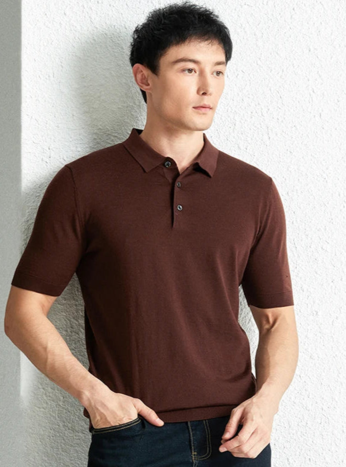 Man wearing a brown polo shirt against a light gray wall