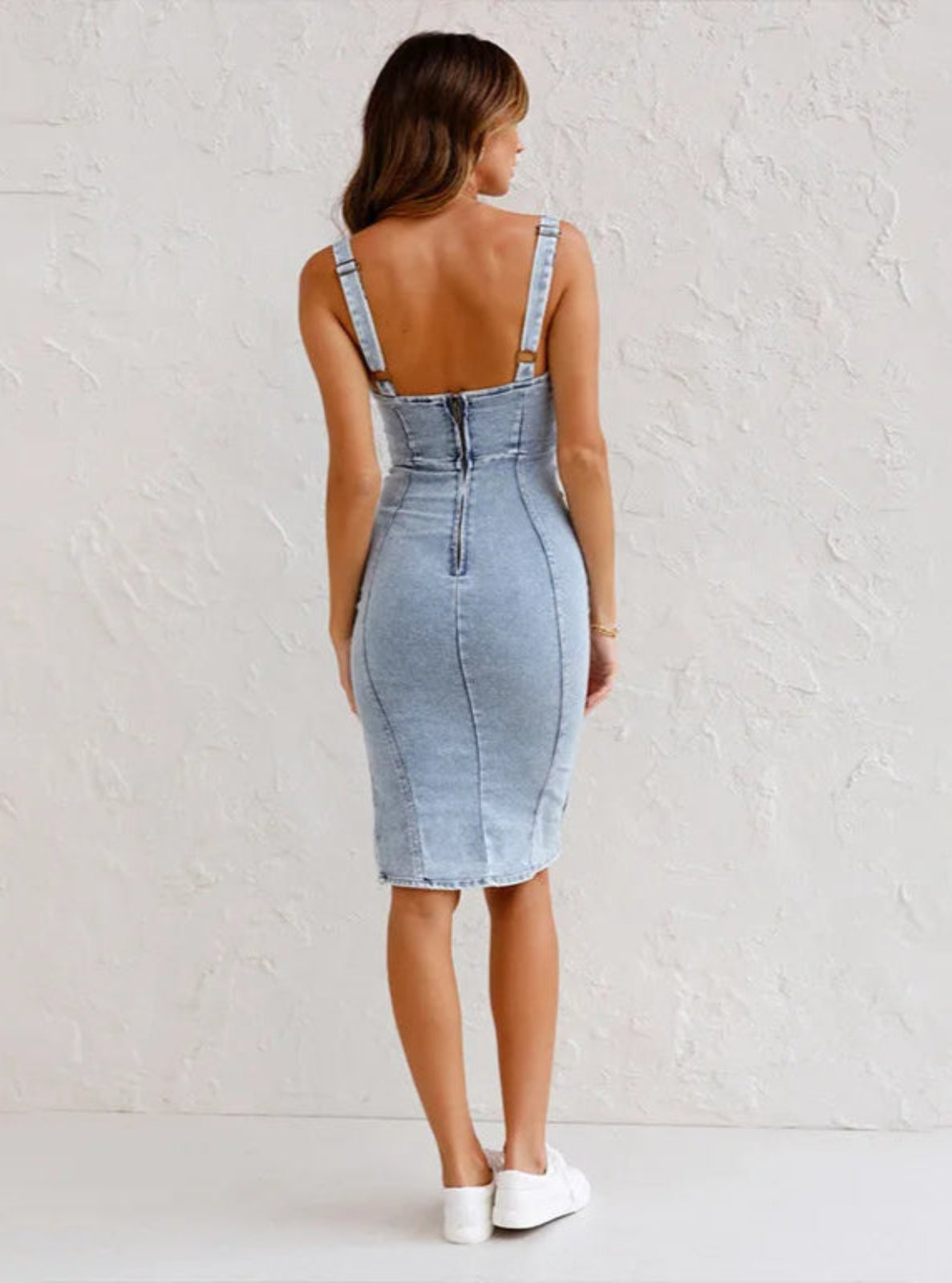 Woman wearing a light blue denim dress against a white background
