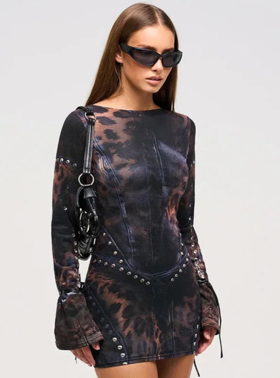 Woman wearing a patterned dress with long sleeves on a plain background