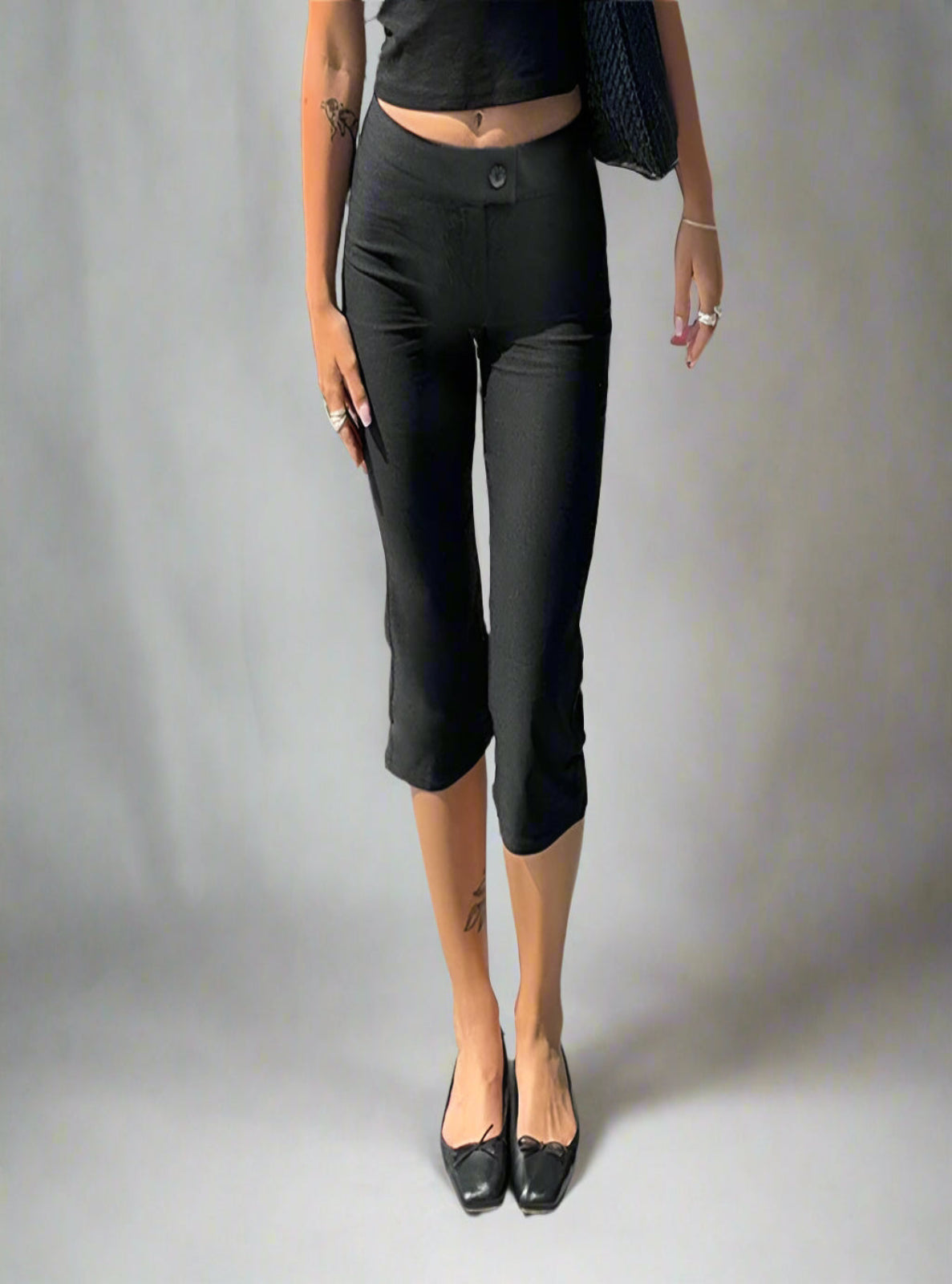 Person wearing black capri pants and black shoes on a white bacground