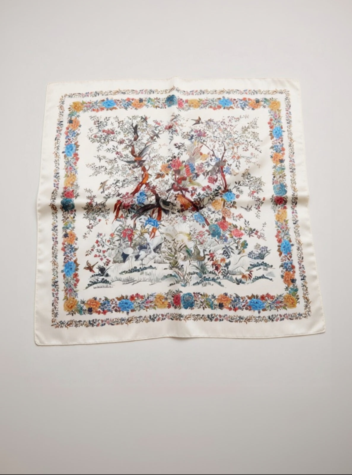 Decorative scarf with floral and animal pattern on a light gray background