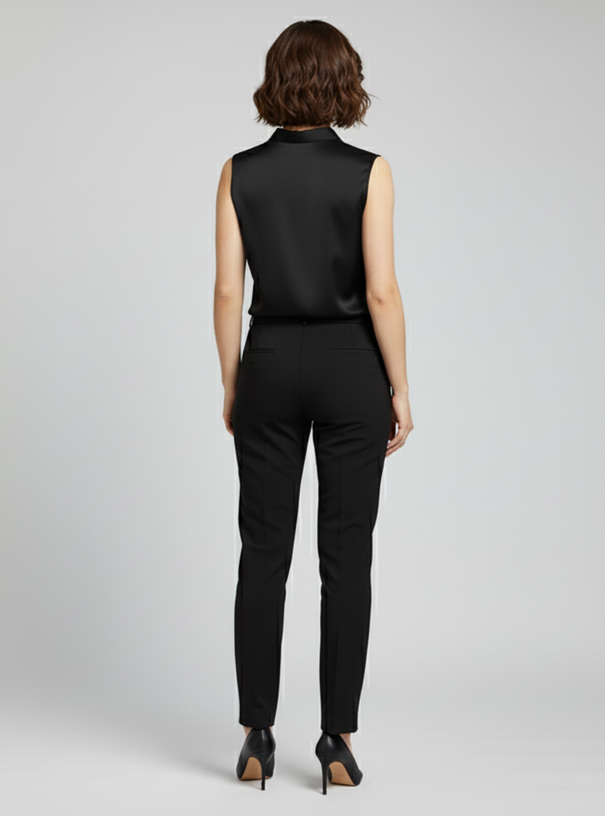 Person wearing a black sleeveless top and pants on a gray background