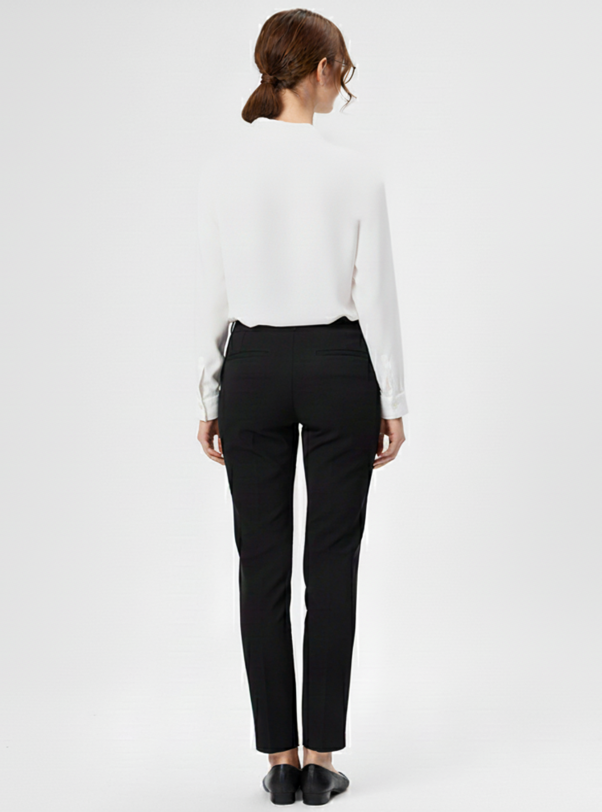 Person wearing a white shirt and black pants on a plain background