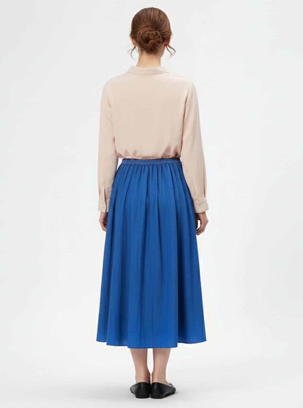 Person wearing a beige blouse and blue skirt on a white background