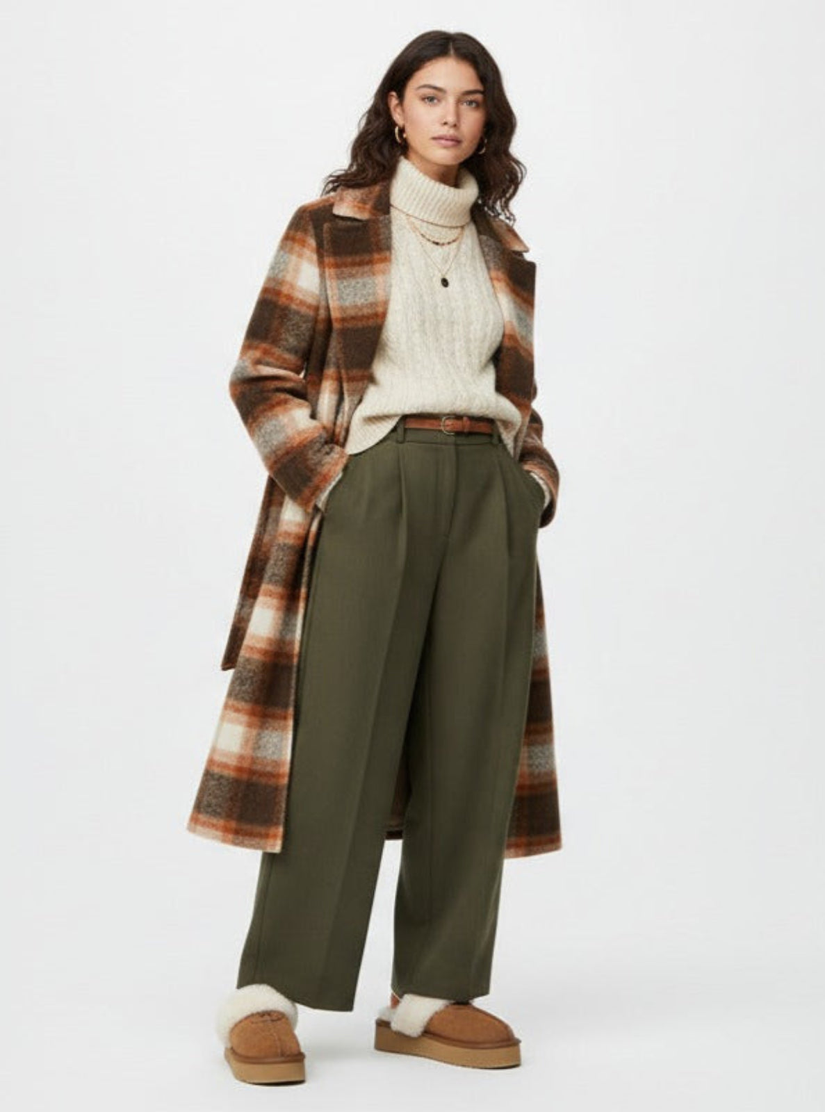 Woman wearing a plaid coat, white sweater, green pants, and brown shoes on a white background