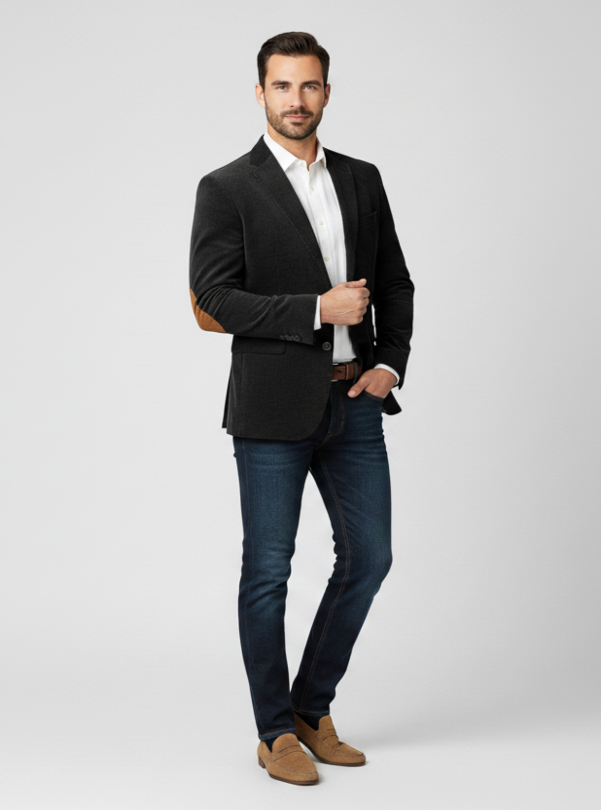Man wearing a black blazer, white shirt, and blue jeans on a light gray background