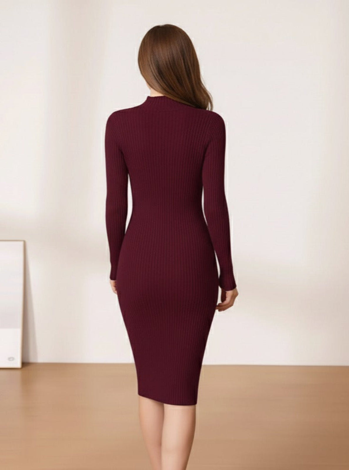 Woman wearing a burgundy dress standing in a minimalistic room with a white wall and wooden floor.