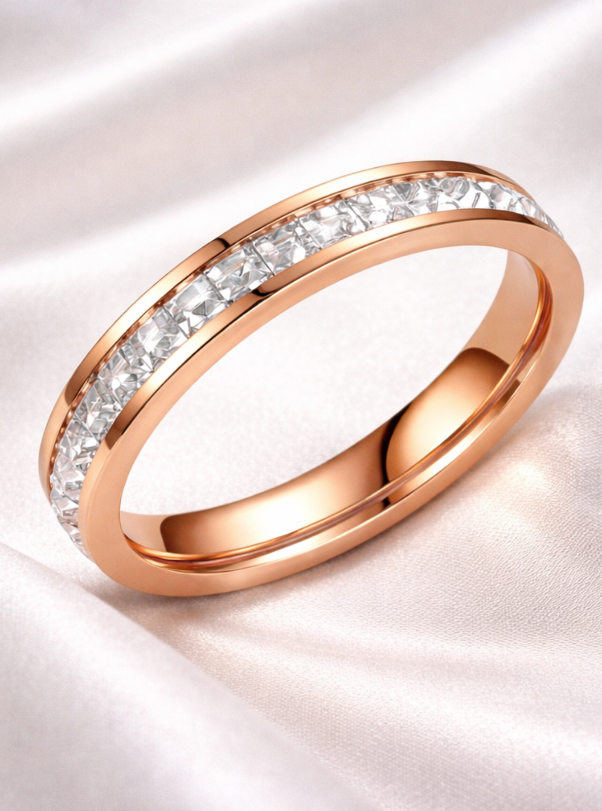 Rose gold ring with diamonds on a white satin background