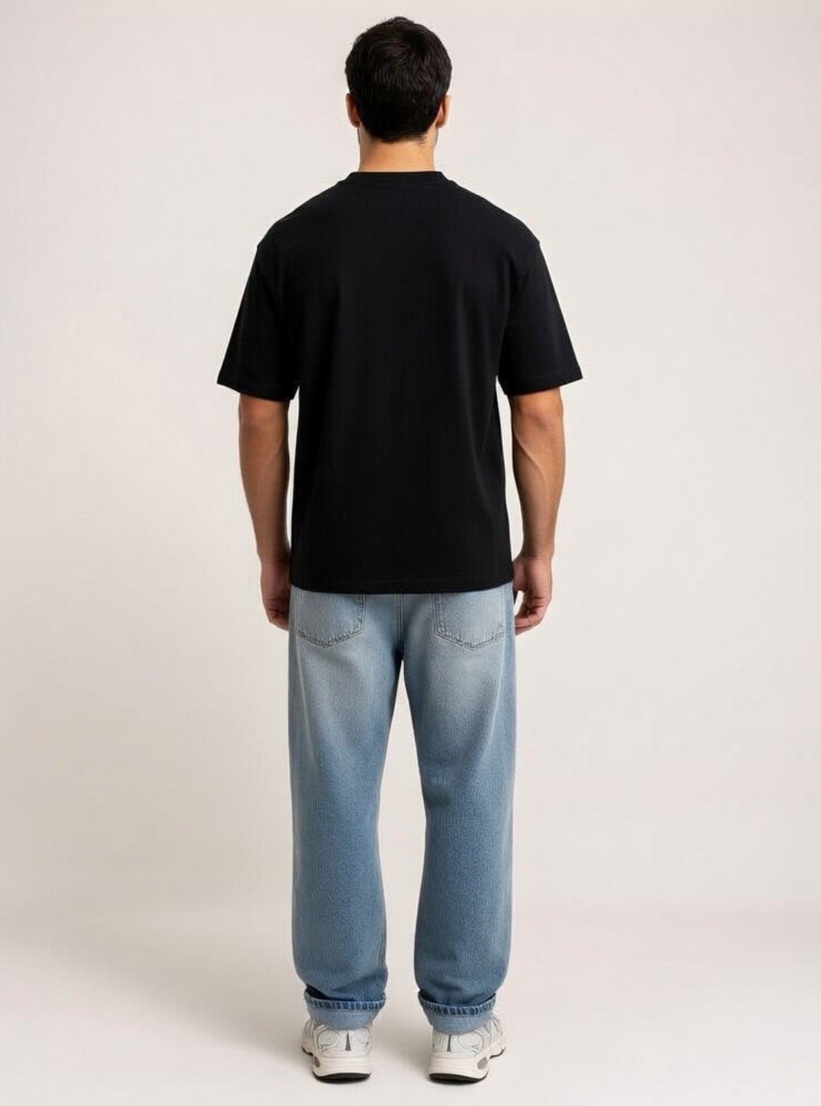 Person wearing a black t-shirt and light blue jeans on a plain background
