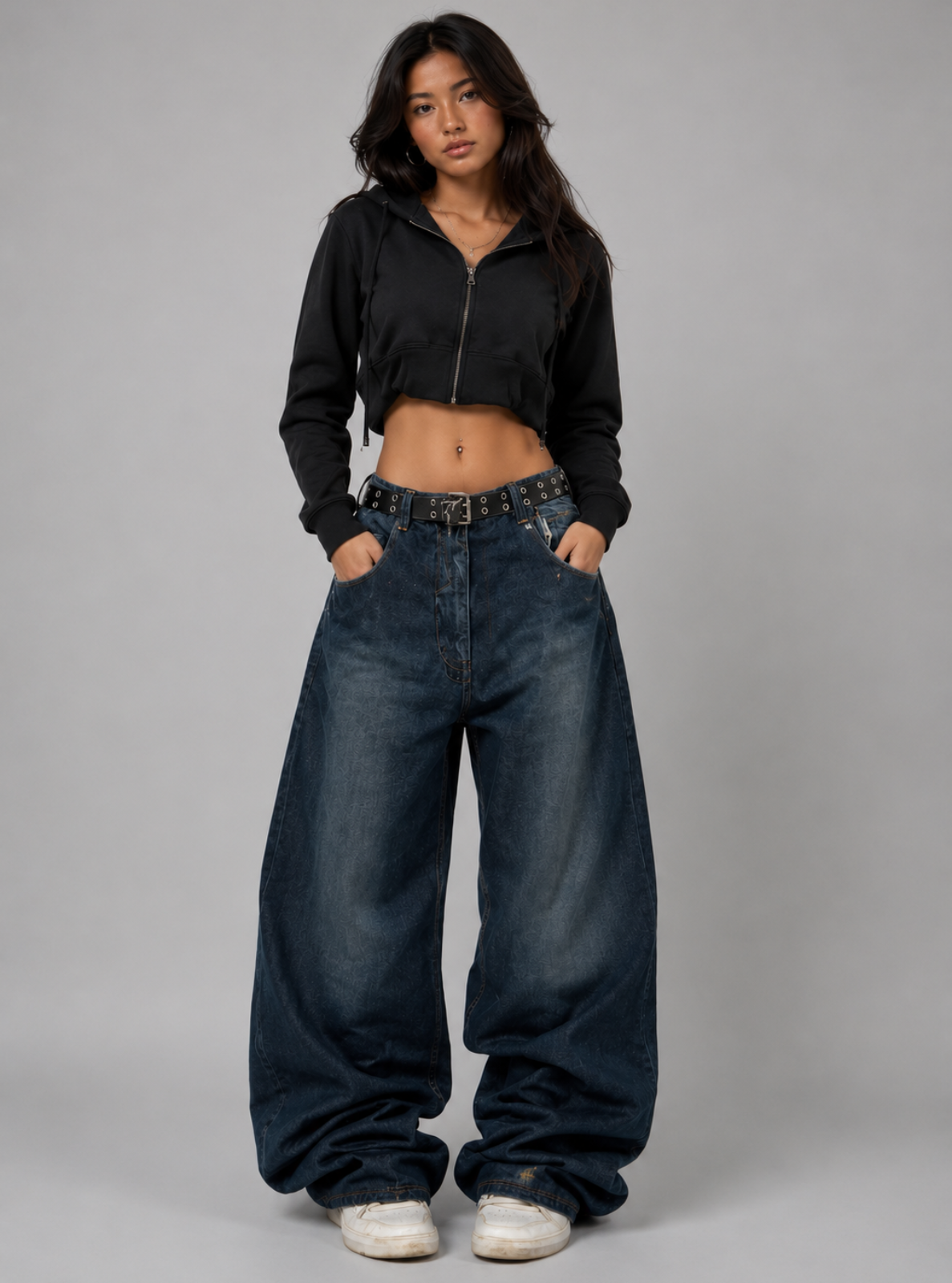 Woman wearing a black cropped jacket and wide-leg jeans on a gray background