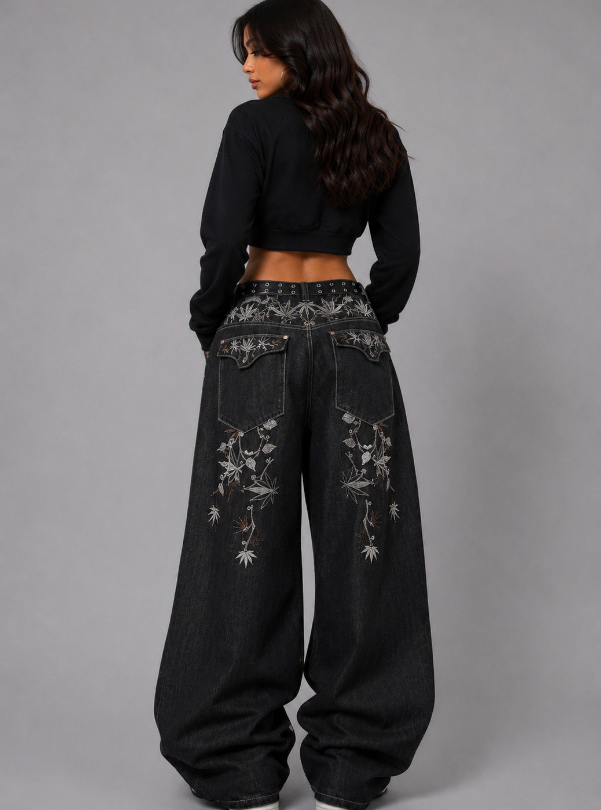 Person wearing black floral embroidered pants and a black top on a gray background