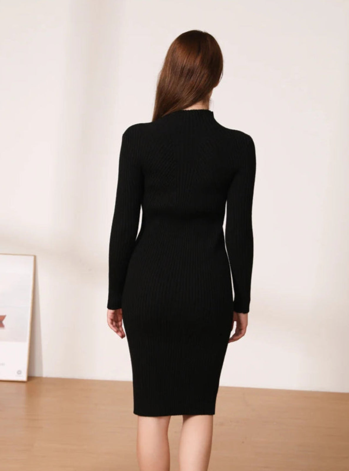 Person wearing a black dress with a plain background